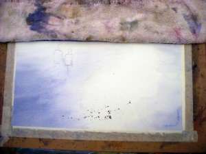 Cover dry sky area before you start splattering watercolor paint in area of pebbles on beach